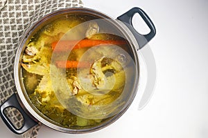 Using metal pot to cook chicken broth with meat and vegetables.