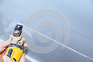 Using a multi-tool to cut plasterboard to lay an electric cable through wall