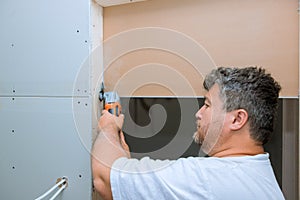 Using a multi tool, worker cuts drywall