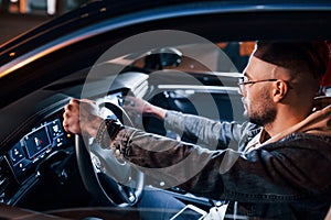 Using navigation display. Handsome unshaved man in fashionable clothes riding his automobile