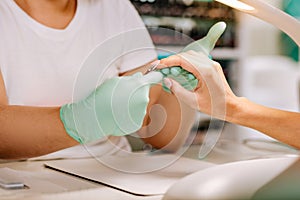 Nail master using nippers while removing cuticle of her client