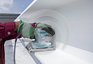 Using a Ponceuse Vibrante or Orbital Sander to scrub surface intermediate fire proof paint before painting top coat photo