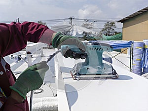 Using a Ponceuse Vibrante or Orbital Sander to scrub surface intermediate fire proof paint before painting top coat photo