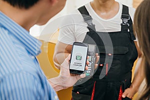 Using smartphone QR code couple pays after moving. Worker holds box