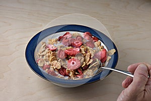 Using spoon to eat a bowl of flake cereal with milk and freeze d