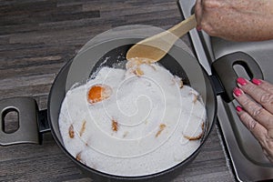 Using a spoon to start mixing the fruit and sugar