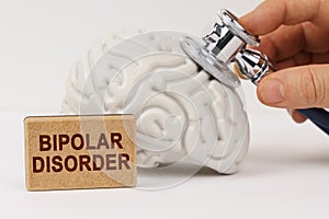 Using a stethoscope, the brain is diagnosed, next to it is a sign with the inscription - Bipolar disorder