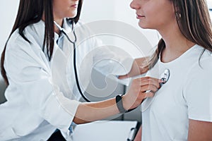 Using stethoscope. Young woman have a visit with female doctor in modern clinic