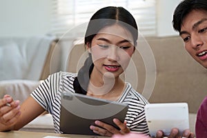 Digital Finance and Cohabitation. A young couple engaging in financial discussions over a tablet, highlighting modern photo