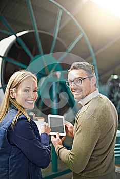 Using technology on the factory floor. Rearview portrait of a two managers using a digital tablet while standing on the