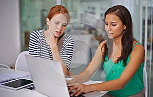 Using technology to be successful in business. two gorgeous young businesswomen working on a laptop.