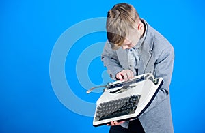 Using a typing machine. Small kid typewriting on old typewriter. Smart schoolboy with vintage typewriter. Cute boy with