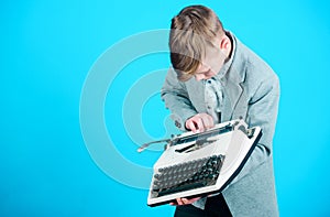 Using a typing machine. Small kid typewriting on old typewriter. Smart schoolboy with vintage typewriter. Cute boy with