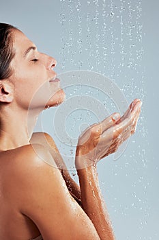 Using water sparingly. a young woman taking a shower against a grey background.