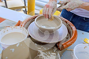 Using wet hands, ceramicist shapes soft clay on a potter wheel photo