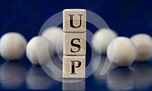 USP - acronym on wooden cubes on a blue background with wooden balls