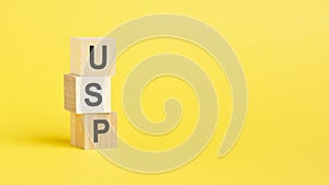 USP - Unique Selling Proposition - text on wooden block with yellow background.