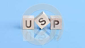 USP word is made of wooden cubes lying on the blue table, concept