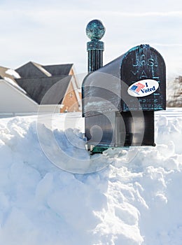 USPS metal mailbox buried in snow drift I voted sticker for vote by mail