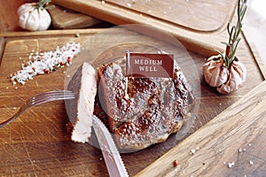 Ñut steak on a wooden board, medium well knife, fork