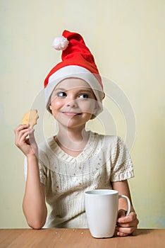 Ð¡ute girl in Santa Claus hat eat cookies.