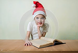 Ð¡ute girl in Santa Claus hat eat cookies.