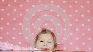 ute little girl falls under the table, disobedience, playfulness, play. Happy child smiling and laughs.