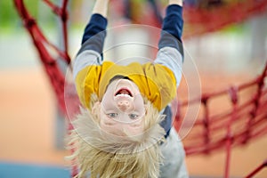 ?ute perky preschooler boy having fun on outdoor playground. Spring summer autumn active sport leisure for kids. Outdoor