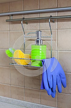 Utensils for washing dishes, liquid, gloves, brush, sponge on metal shelf in kitchen. Concept of decanting detergents, no labels