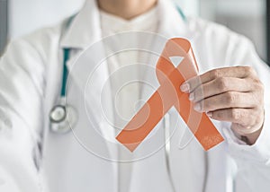 Uterine and Gynecologic Cancer Awareness peach color ribbon isolated with clipping path in doctorÃ¢â¬â¢s hand photo