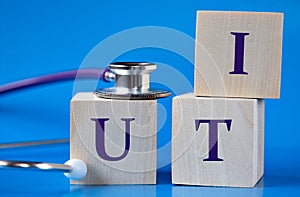 UTI - acronym on wooden large cubes on blue background with stethoscope