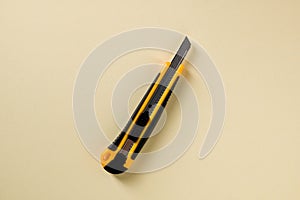 Utility knife with yellow and black handle on a yellow background