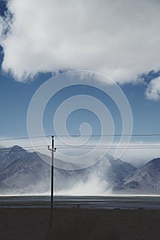 Utility pole and steam rising in front of mountains