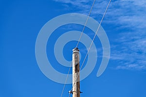 A utility pole supports two cables with a clear blue sky