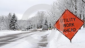 UTILITY WORK AHEAD sign warns traffic about a work crew on a snowy city street, on a frosty winter day