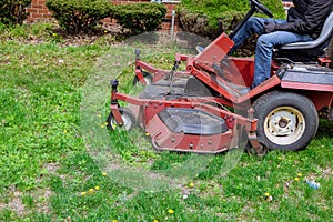 Utility worker in lawn mower gardener cutting the grass ride-on lawnmower