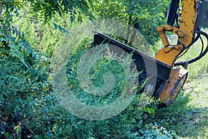 A utility worker using a professional tractor mechanical mower mowing grass mowing tall grass along the side