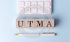 UTMA on wooden cubes with pen and calculator, financial concept