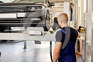 Ðuto mechanic sets the car for diagnostics and configuration collapse-convergence. Car Wheels alignment equipment on stand in a