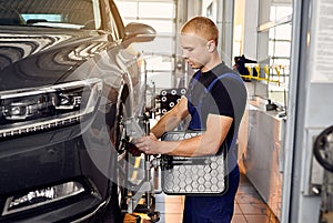 Ðuto mechanic sets the car for diagnostics and configuration collapse-convergence. Car Wheels alignment equipment on stand in a