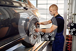 Ðuto mechanic sets the car for diagnostics and configuration collapse-convergence. Car Wheels alignment equipment on stand in a