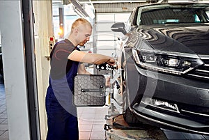 Ðuto mechanic sets the car for diagnostics and configuration collapse-convergence. Car Wheels alignment equipment on stand in a