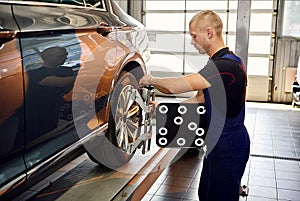 ÃÂuto mechanic sets the car for diagnostics and configuration collapse-convergence. Car Wheels alignment equipment on stand in a photo