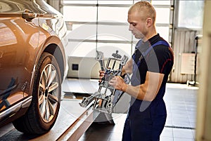 Ðuto mechanic sets the car for diagnostics and configuration collapse-convergence. Car Wheels alignment equipment on stand in a