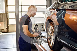 ÃÂuto mechanic sets the car for diagnostics and configuration collapse-convergence. Car Wheels alignment equipment on stand in a photo