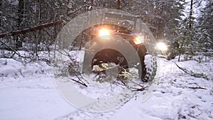 UTV sxs off-road vehicle drives around a a fallen tree in the winter forest