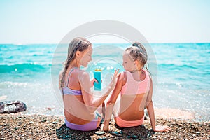 UV protection. Sister puts sunscreen on her little sister`s nose