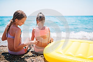 UV protection. Sister puts sunscreen on her little sister`s nose