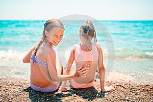 UV protection. Sister puts sunscreen on her little sister`s nose