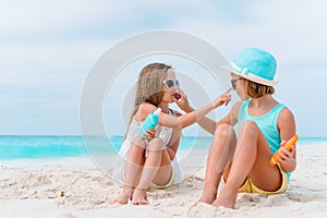 UV protection. Sister puts sunscreen on her little sister`s nose